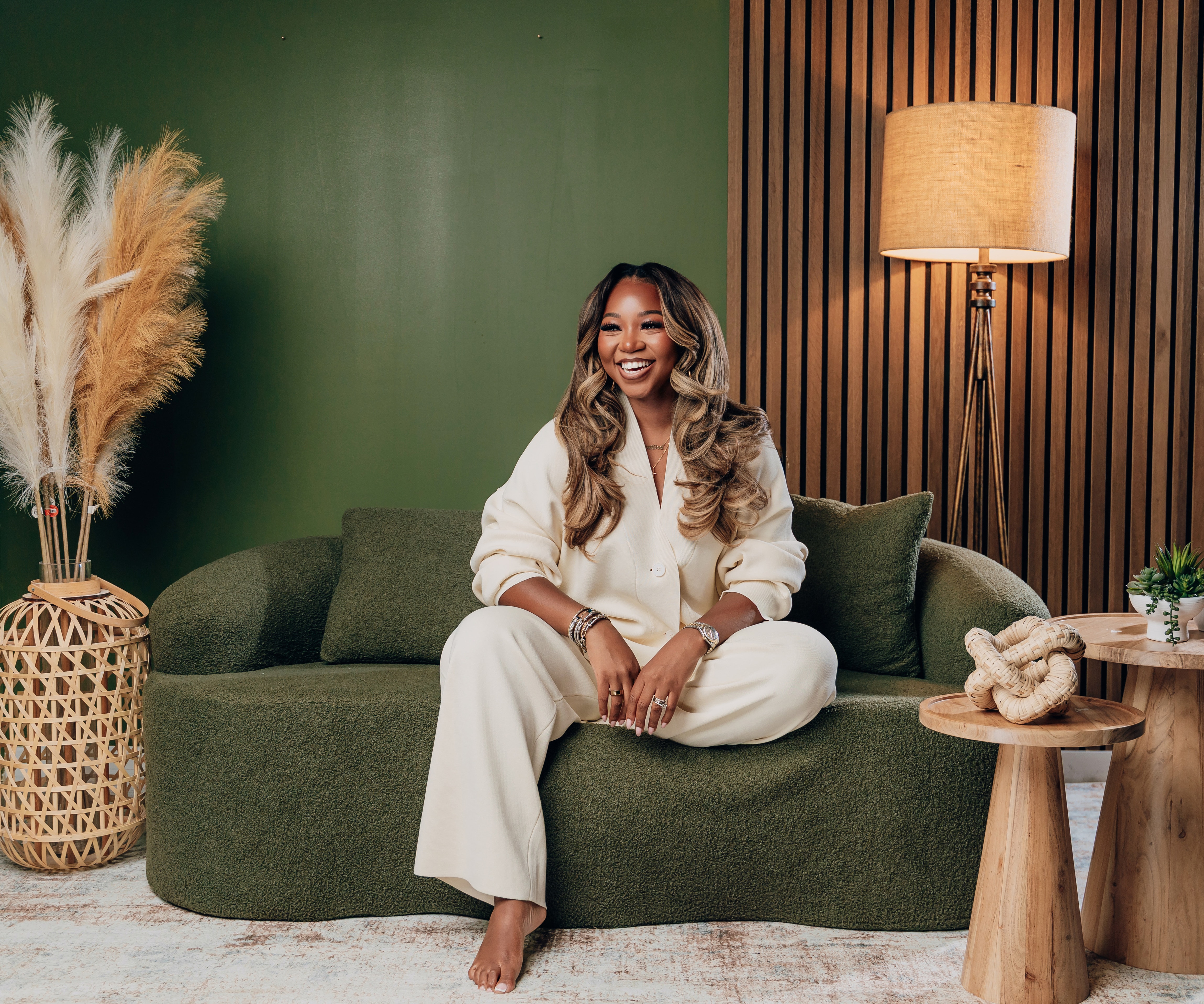 Janesha Moore seated on a green sofa in a warm lounge