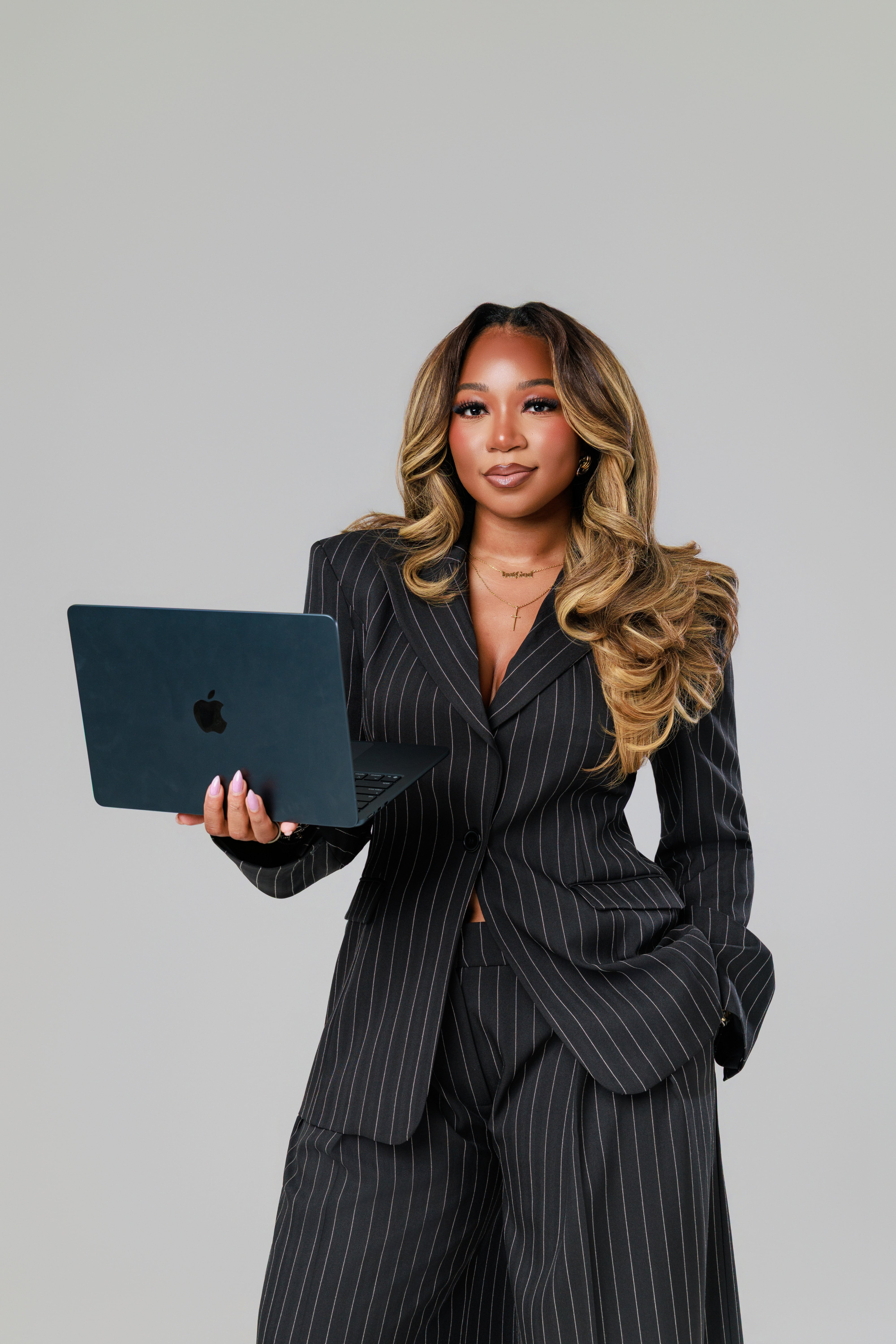 Janesha with a laptop in pinstripe